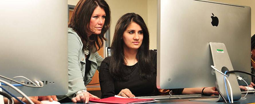 student at a computer being helped by a support person